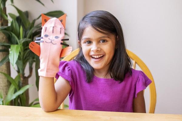 A child smiles with her kitty cat puppet craft.