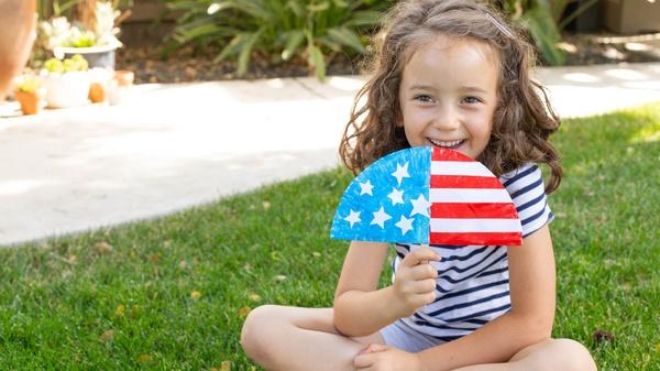 Child fanning themselves with a flag fan.