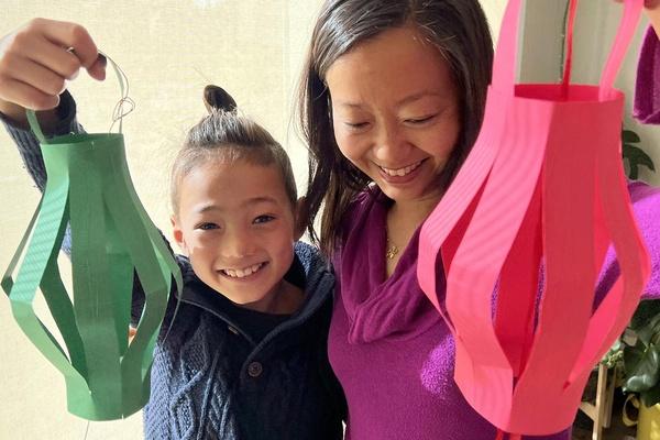 A parent and child hold up their paper lanterns.