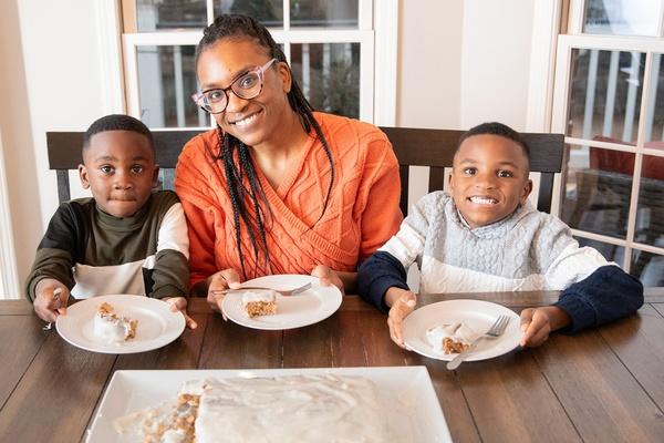 A parent and her children eat carrot cake together.