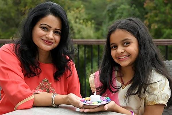 A parent and child hold their finished DIY diya.