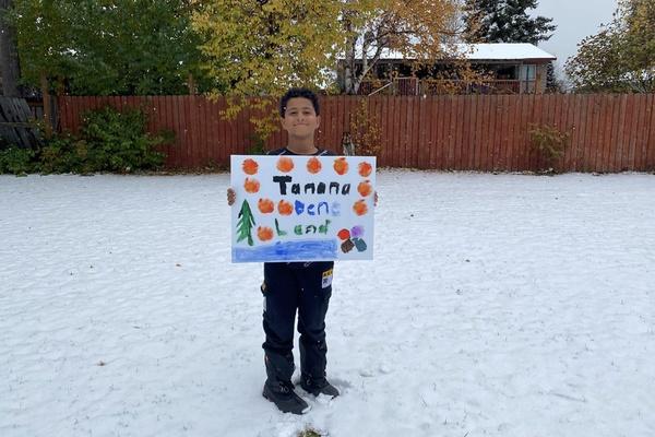 A child holds a land acknowledgement poster.
