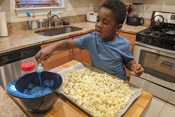 A child spoons out candy coating from a bowl.