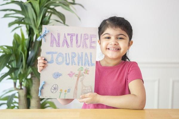 A girl holds up her animal observation journal.