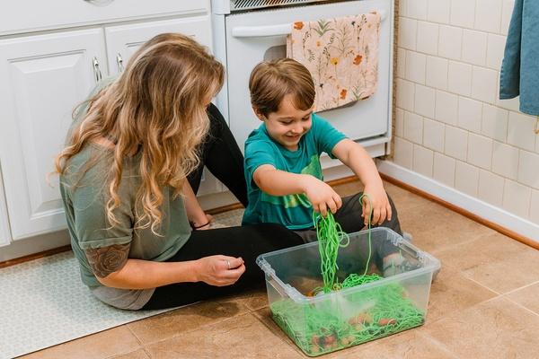 A parent and child explore their monster swamp sensory bin.