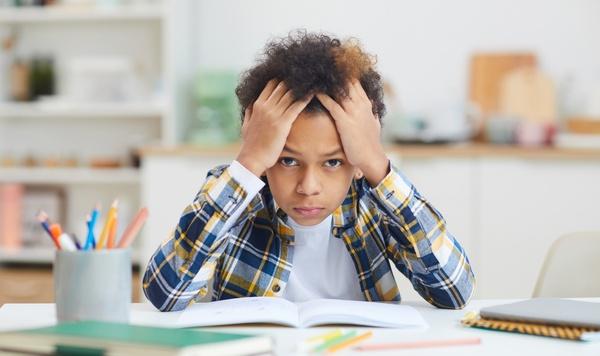 Young boy looking frustrated while doing homework.
