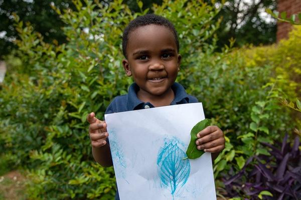 A boy holds his leaf rubbing.