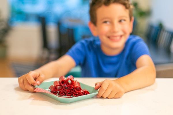 Boy holding tray of rolled fruit snacks.