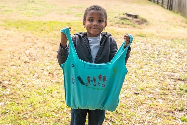 Un niño sostiene una bolsa que hizo con una camiseta.