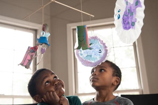 Two boys look at ocean mobile they made.