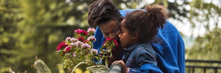 Image of mother and daughter smelling flowers.