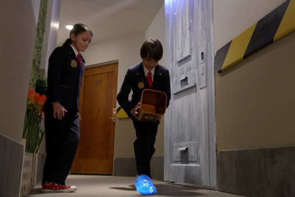 Odd Squad agents following a blob down a hallway.