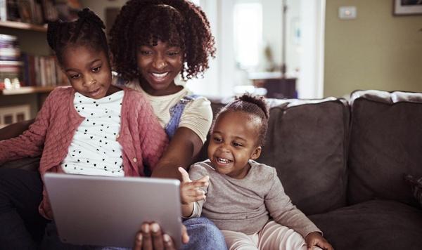 Mom and two daughters looking at a tablet.