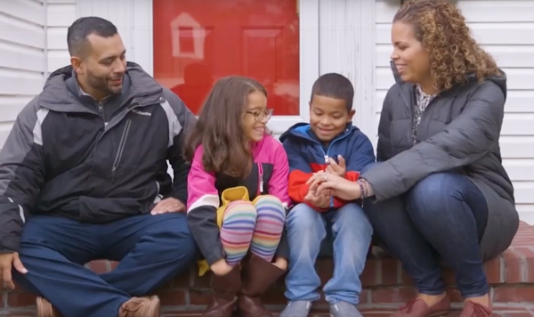 Image of two parents and with two kids sitting outside together.