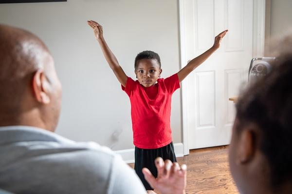 Child dancing as an animal in front of family