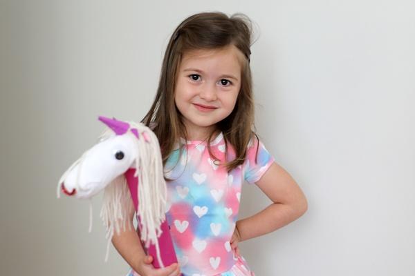 A girl holds her galloping unicorn.