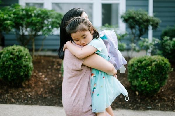 Preschooler with a backpack hugging mom.