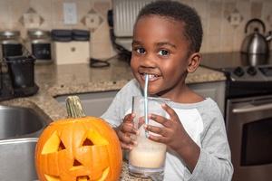 Child holding a pumpkin smoothie.