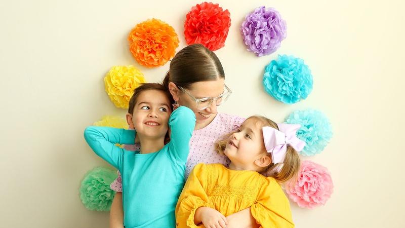 A family stands in front of a paper flower arch that they made.