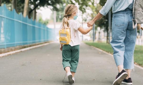 Young girl holding hands and walking with her mom.