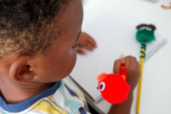 A child uses pencils with Sesame Street Pencil Toppers