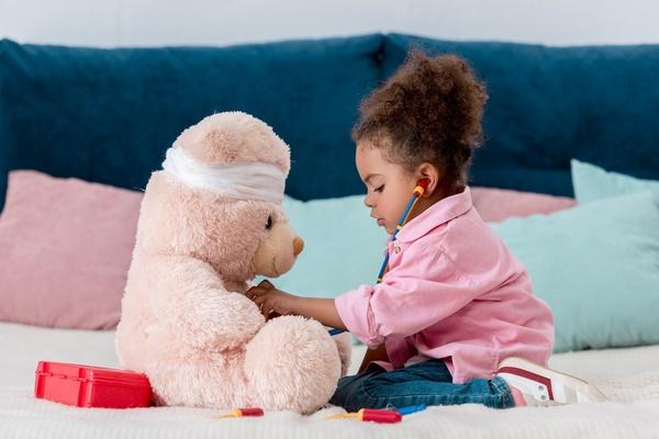 Child using a stethoscope on a stuffed bear.