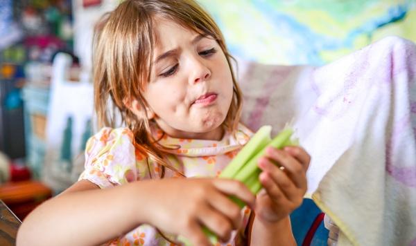 Young girl looking at celery.