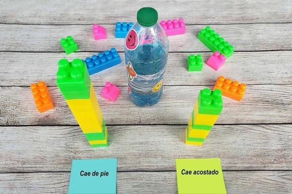 A water bottle with sparkly blue water stands alongside two towers of colorful plastic blocks representing the number of "stands" and "falls" in this fun bottle-flipping game.