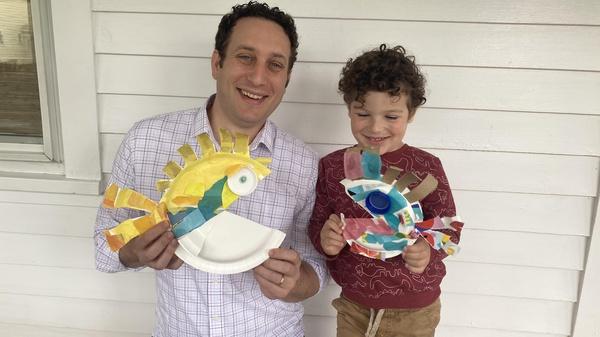 Father and son hold up their finished fish crafts.