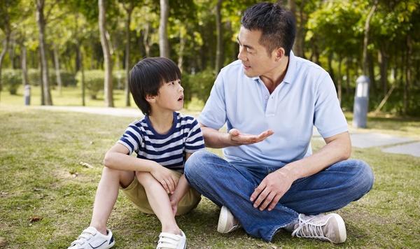 Father talking to young son outside.