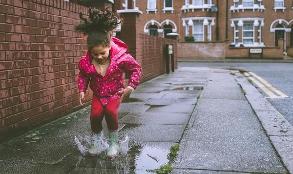 Image of young girl playing in a puddle.