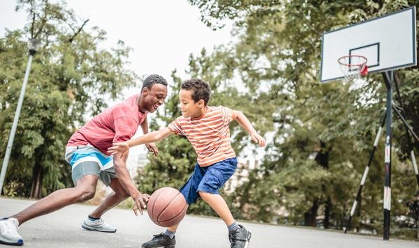 A father and son playing basketball together.