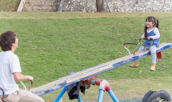 Father and daughter balancing on a seesaw.
