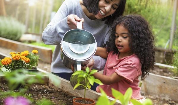 Mother and daughter watering plants at a community garden.