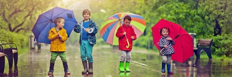 Children standing outside with umbrellas after a rain storm.