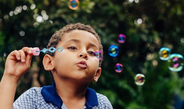 Boy blowing bubbles outside.