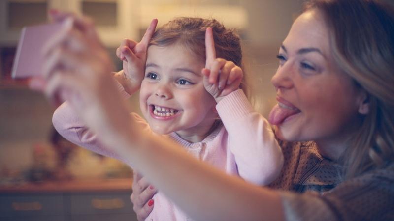 Una madre y su hija ponen caras graciosas mientras posan para una selfie.