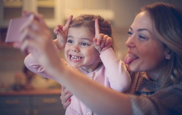Mother and child make funny faces while posing for a selfie.