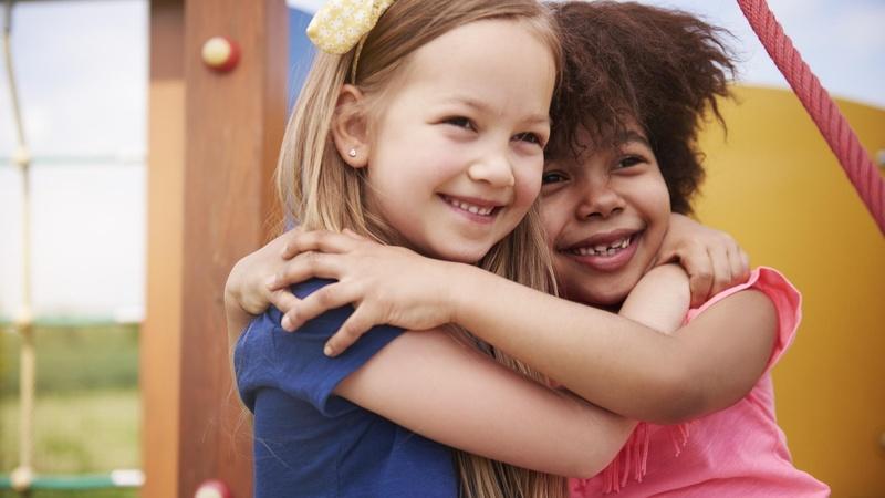 Two children hugging while playing at the park.
