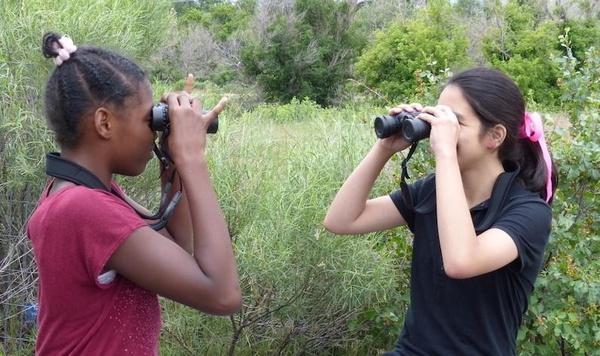 Two girls looking through binoculars.