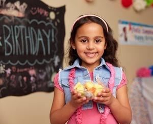 Girl holding a bowl of tropical fruit salad.