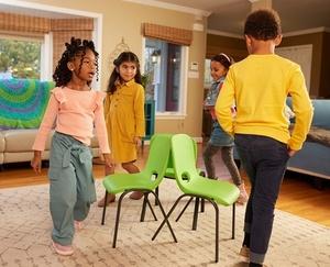 Children marching around chairs in a circle while music plays.