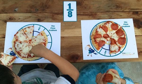 2 pizzas sitting on printables showing fractions.