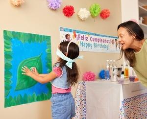 Mom watching as a party guest pins a paper frog on a poster.