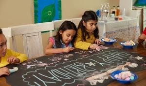 Children drawing on a banner with chalk at an Alma's Way birthday party.