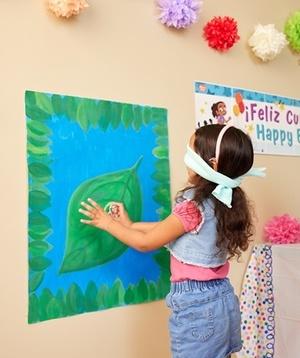 Child playing Pin the Coqui Frog on the Leaf game.