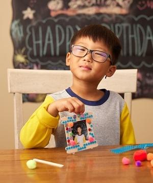 Child showing off his picture frame art.