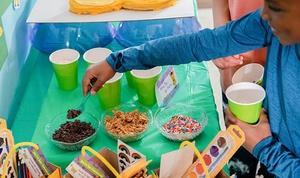 Child adding topping to froyo bites.