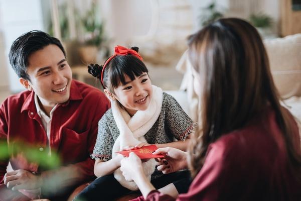 Parents giving red envelope to their daughter.