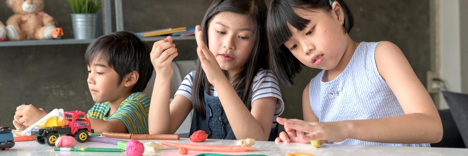 Image of three kids playing with playdough.
